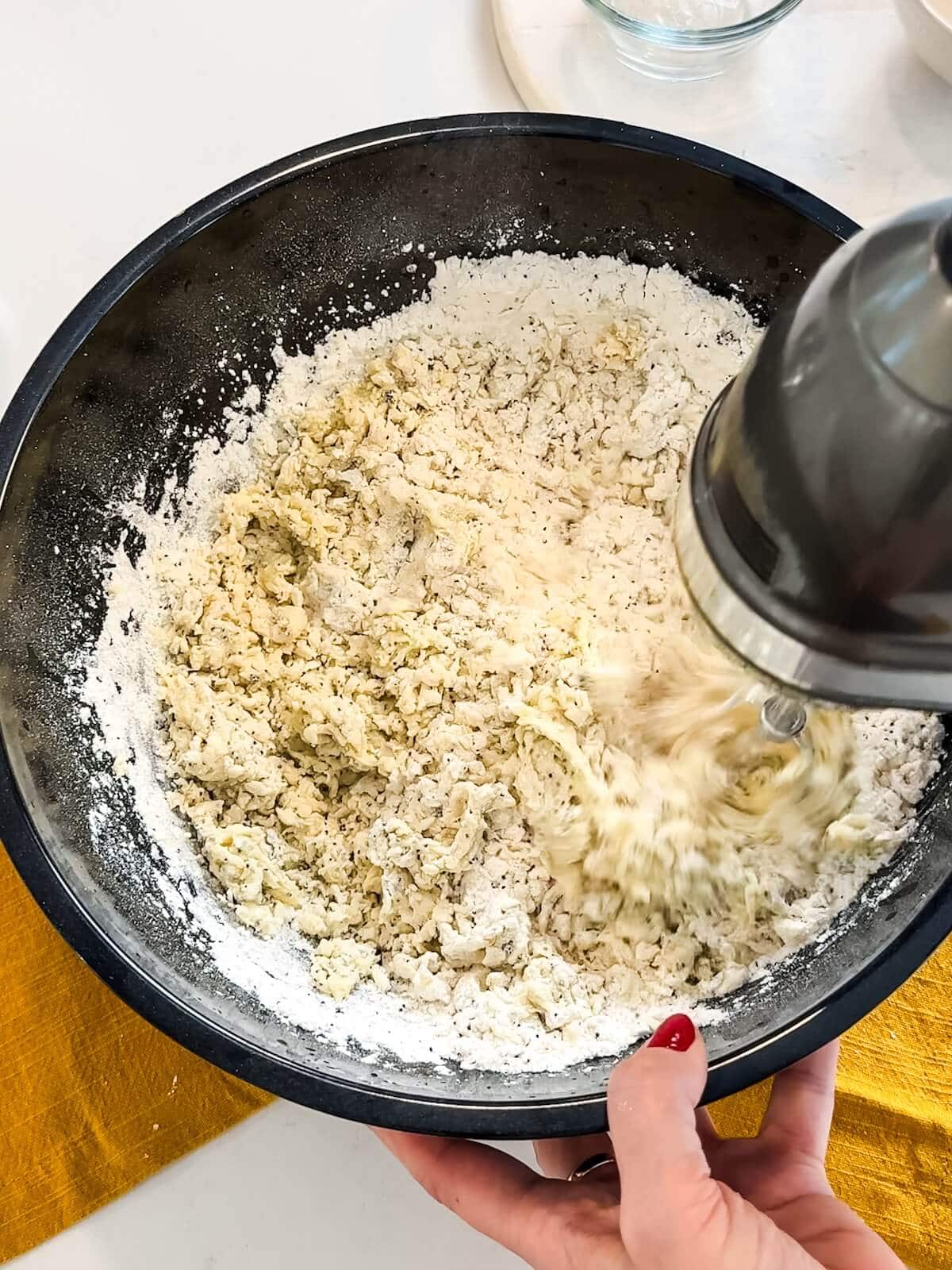 stirring dry ingredients into wet ingredients with a mixer for lemon poppyseed cookies.