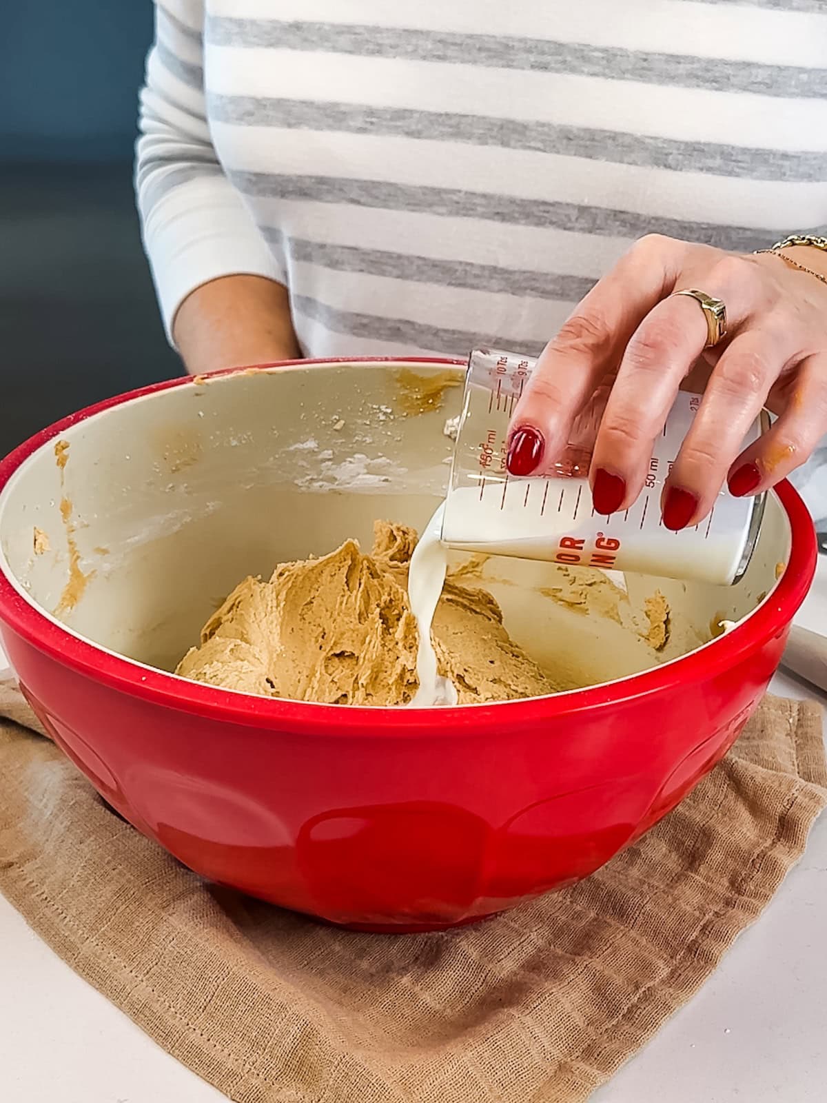 adding milk to thick peanut butter frosting.