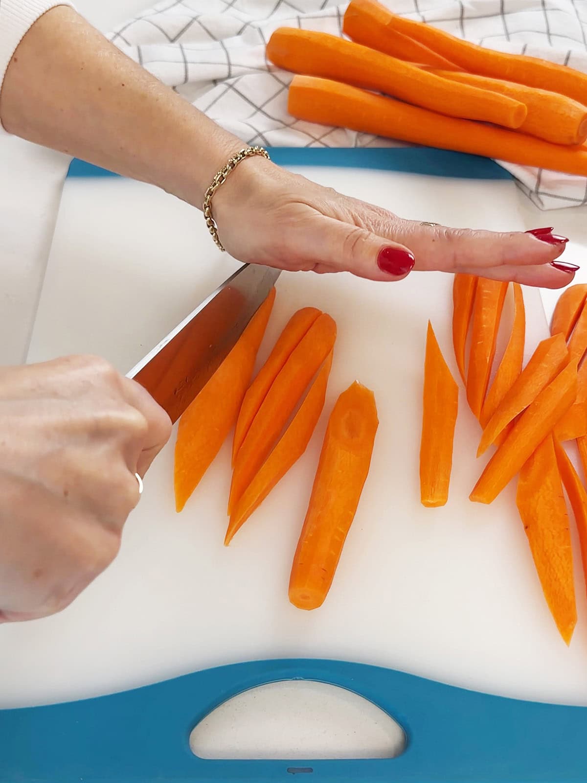cutting peeled carrots into irregular matchsticks for roasted carrots.