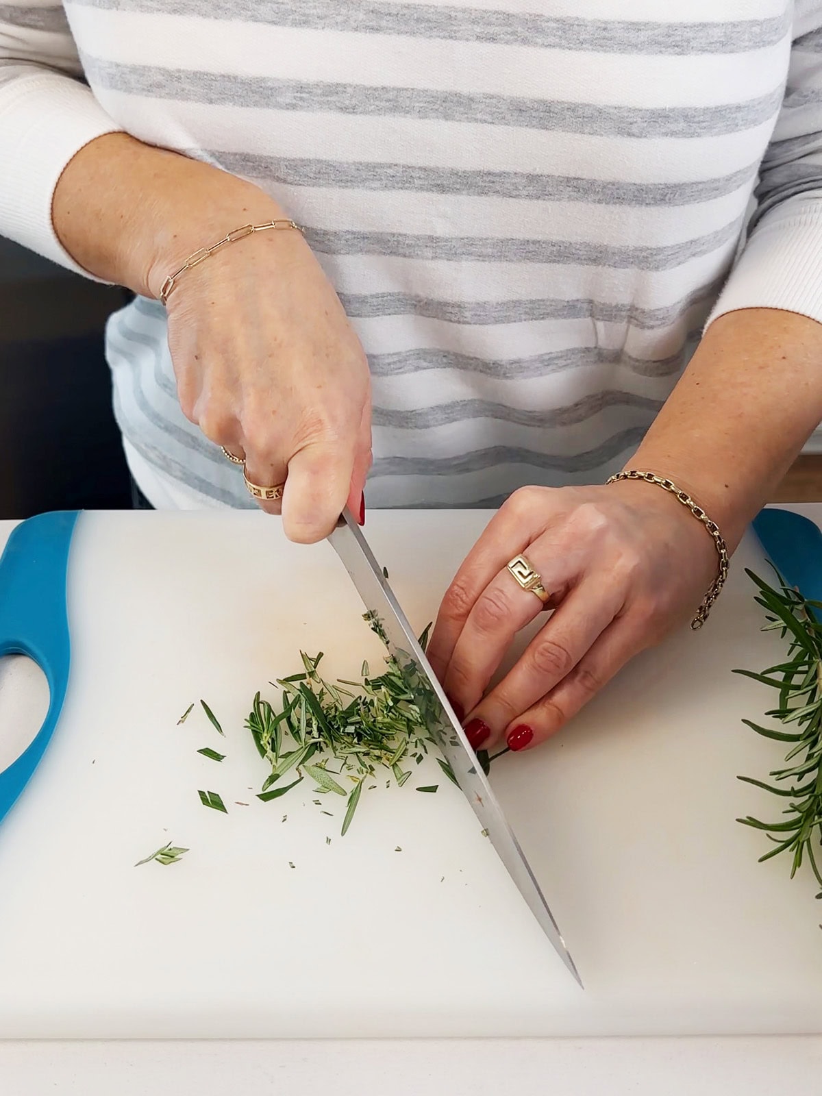 chopping rosemary with a chef knife.