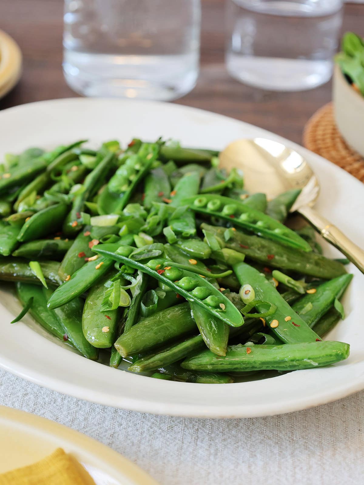 A serving dish filled with sauteed sugar snap peas.