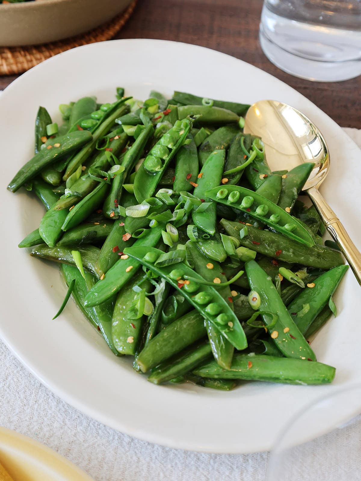 Close up of a serving dish filled with sauteed sugar snap peas.