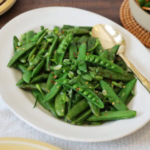 A serving dish filled with sauteed sugar snap peas.