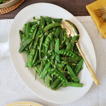 Overhead view of a serving dish filled with sauteed sugar snap peas.