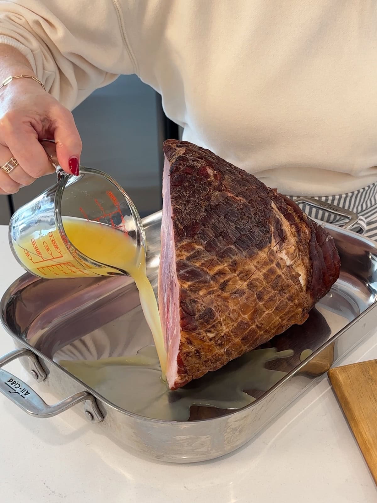 Adding pineapple juice and water to pan with ham before roasting.