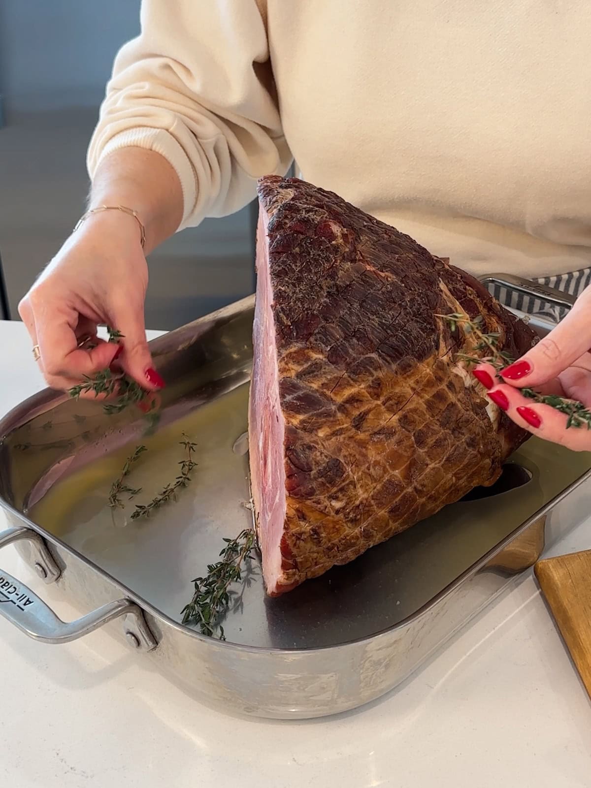 Adding herbs to pan with a ham before roasting.