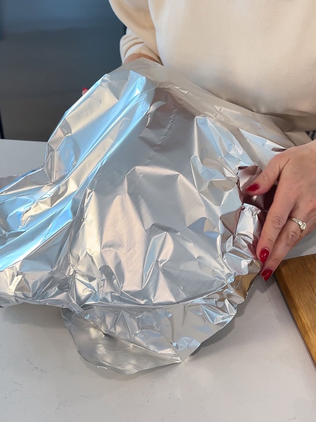 covering a roasting pan with a ham with aluminum foil for roasting.