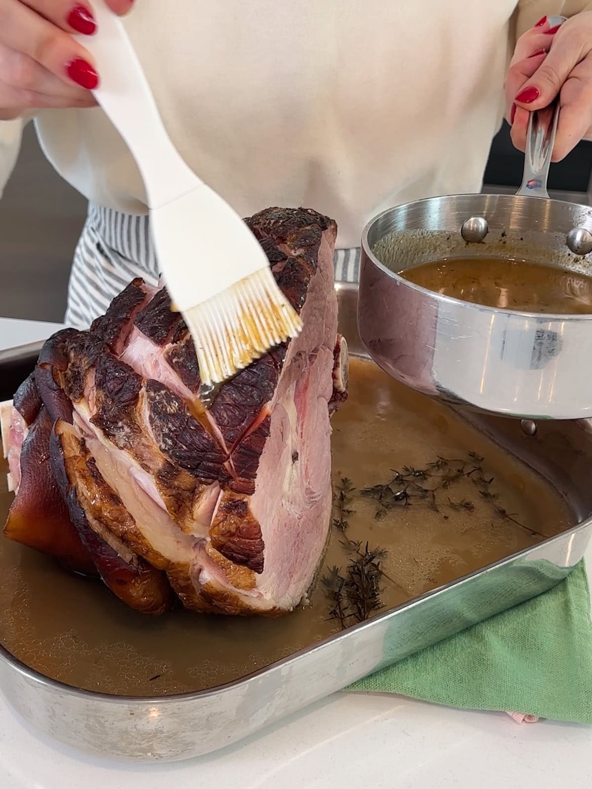 Basting a cooked ham with a pineapple sauce glaze.