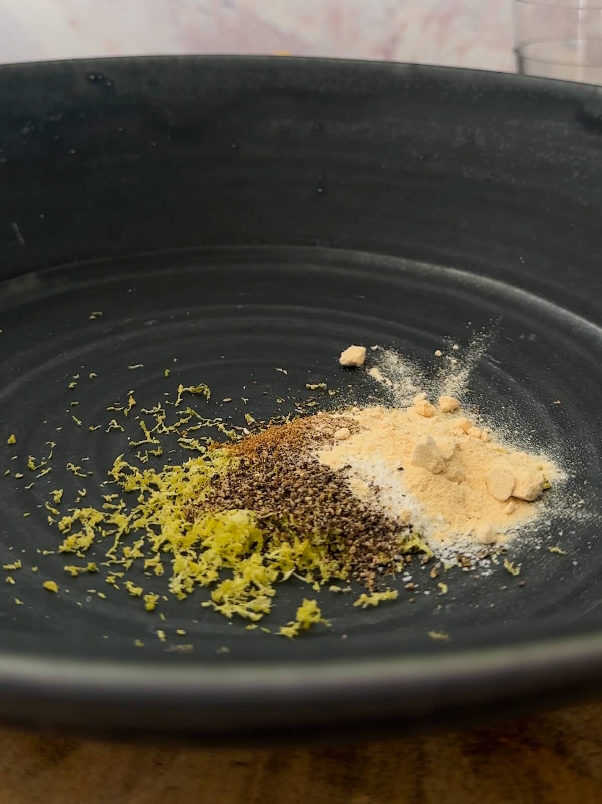 lemon zest, spices, and salt in the bottom of a bowl in preparation to make dressing for quinoa chickpea salad.