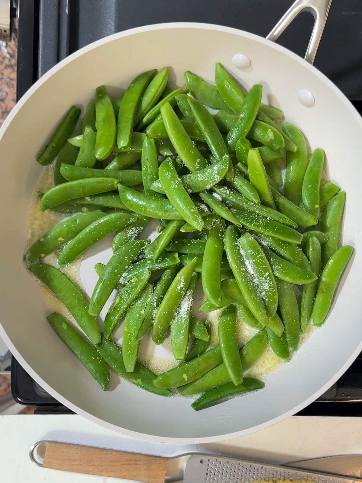 Melted butter, sugar snap peas, and kosher salt in a nonstick skillet