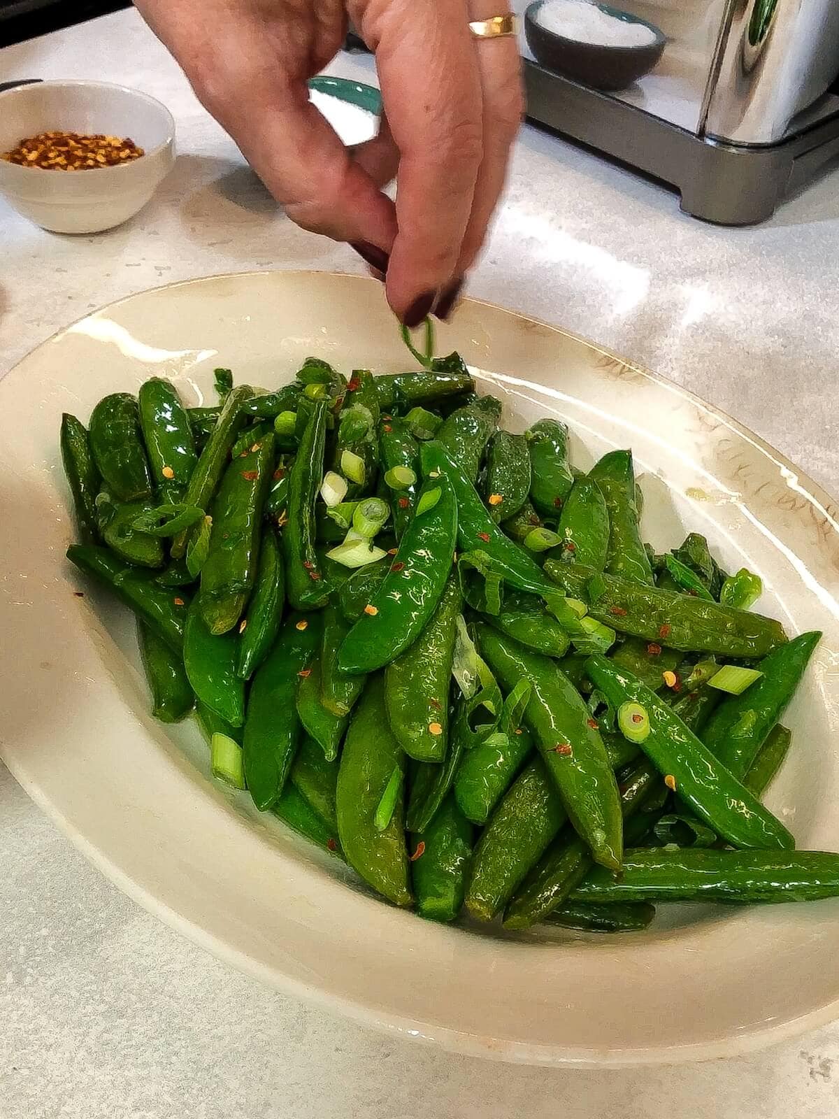 garnishing sauteed sugar snap peas with fresh scallions
