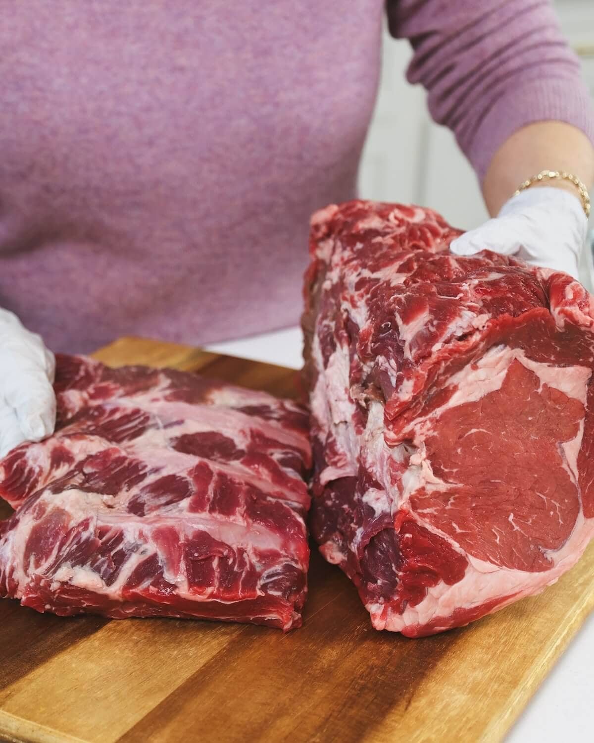 Hands holding a prime rib roast separated from the rib bones preparing for cooking.