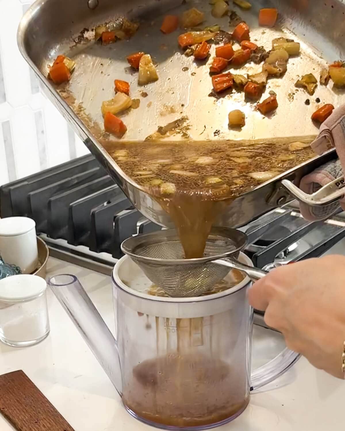 Pouring pan sauce from roasting pan through a fine mesh strainer.