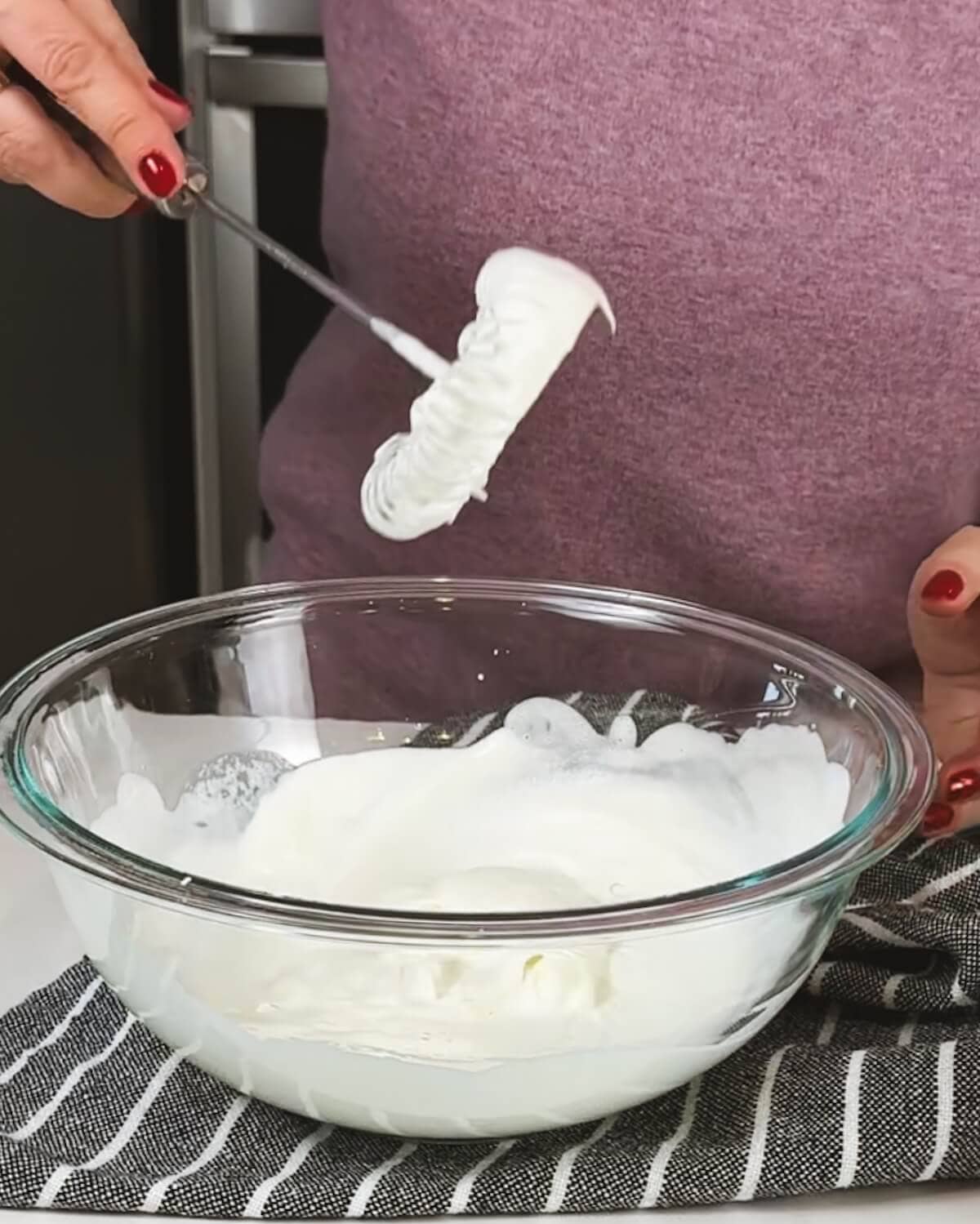 Whisking heavy cream to soft peaks in a glass bowl.