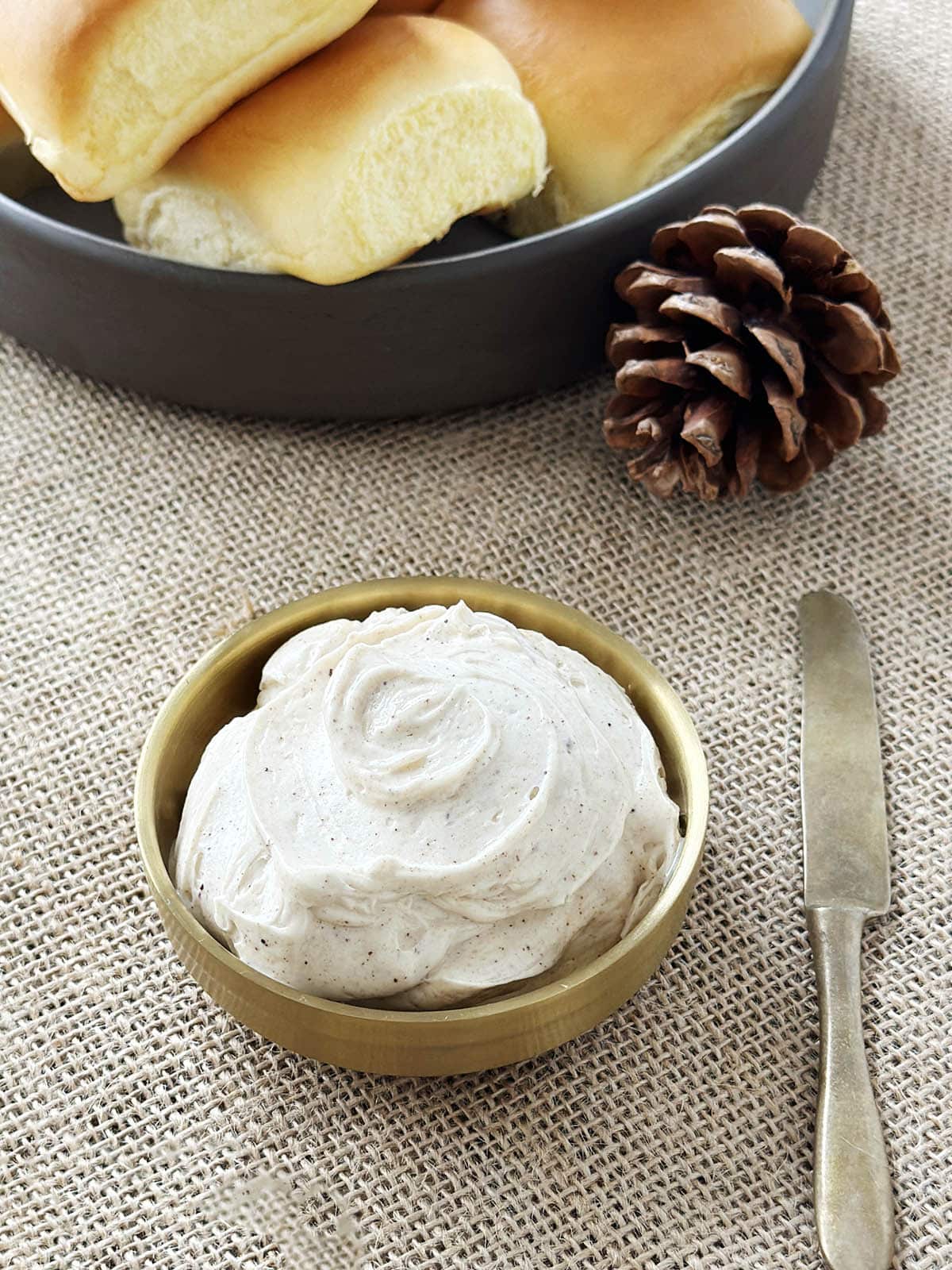 A bowl of whipped browned butter next to a butter knife.