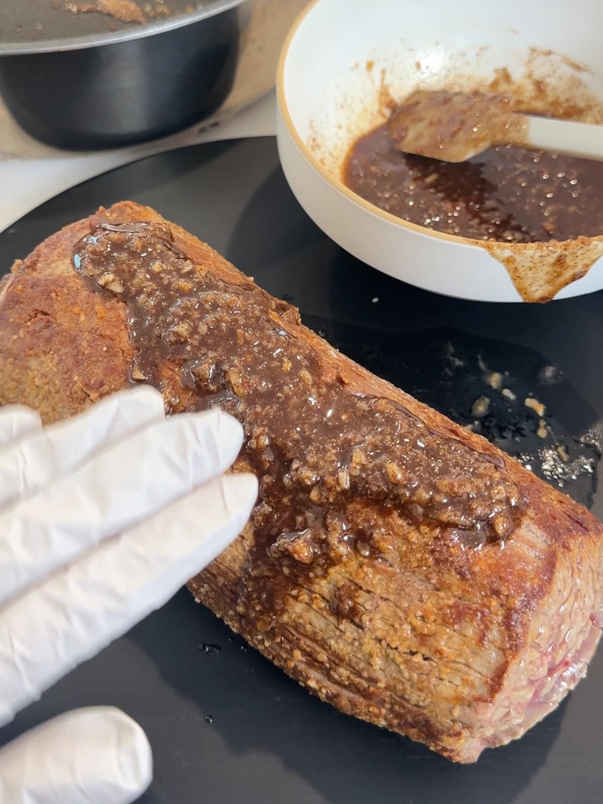 using a gloved hand to rub spice mixture on browned beef tenderloin before roasting.