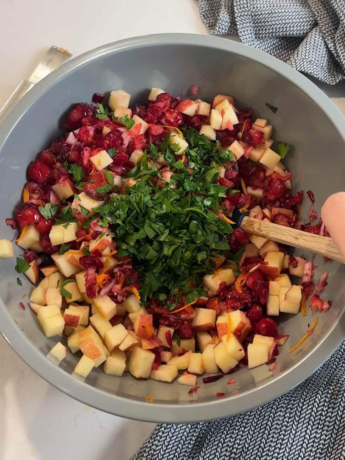 adding chopped parsley to bowl of cranberry relish.