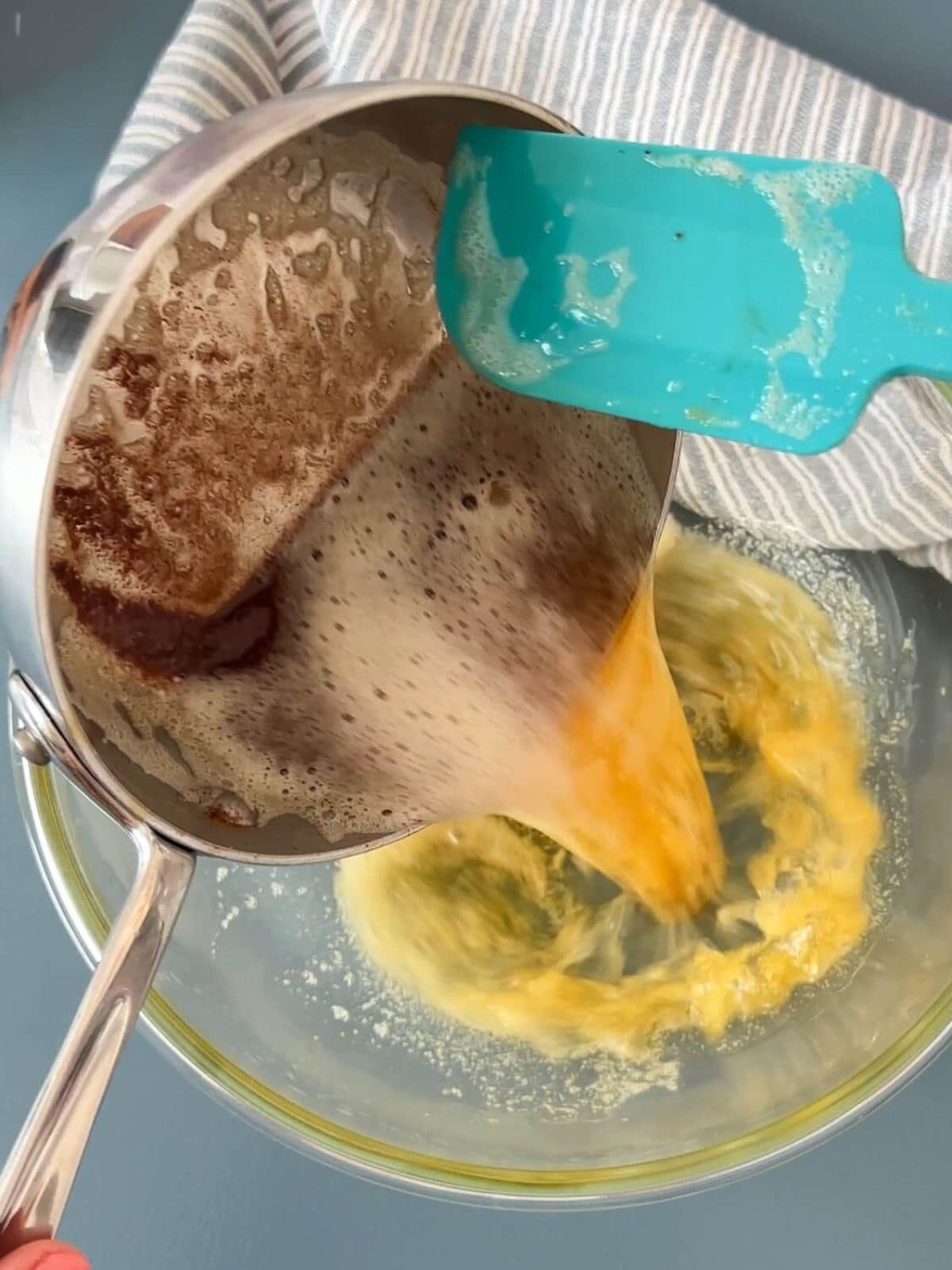 Pouring browned butter into a glass bowl.