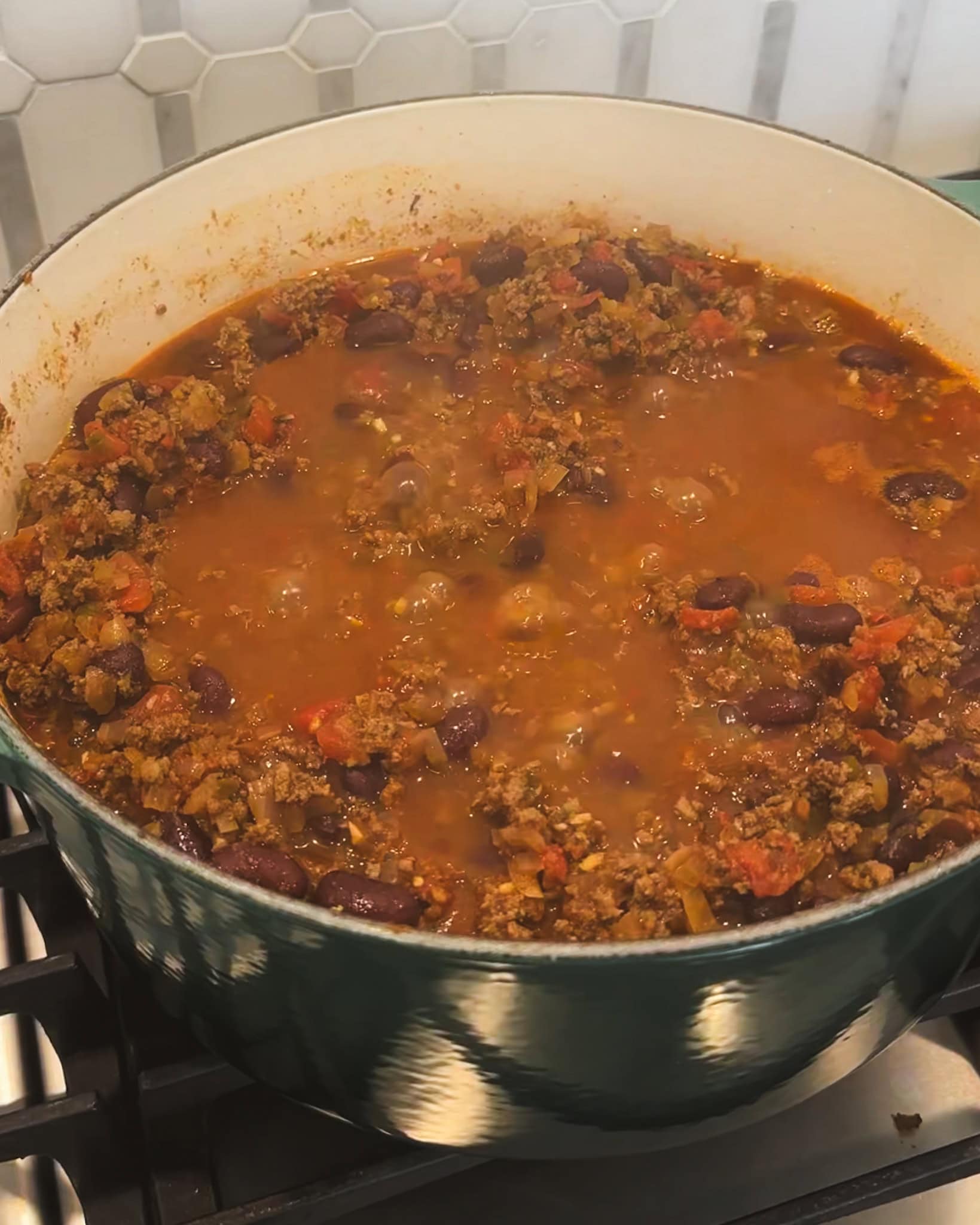 pot of simmering ground beef chili on the stove.
