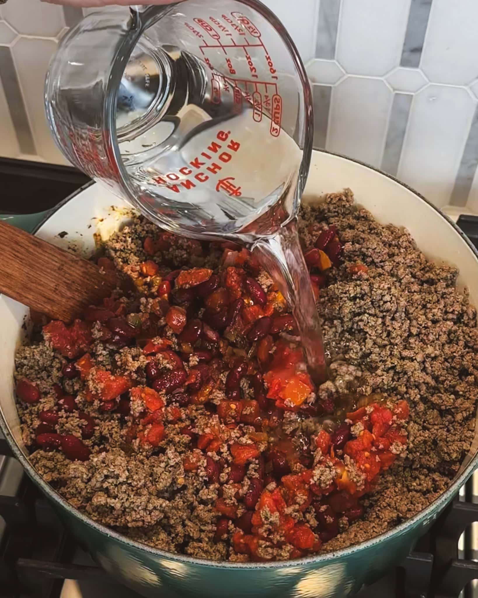 Pot of ground beef, tomatoes and beans with water for chili.