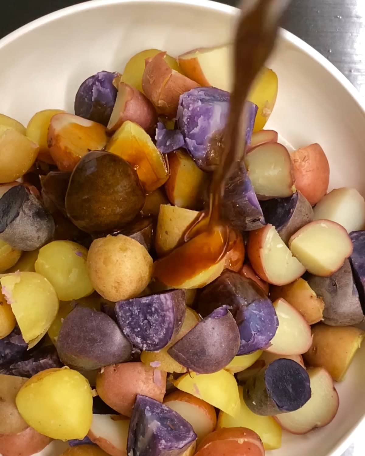pouring balsamic dressing on cooked potatoes