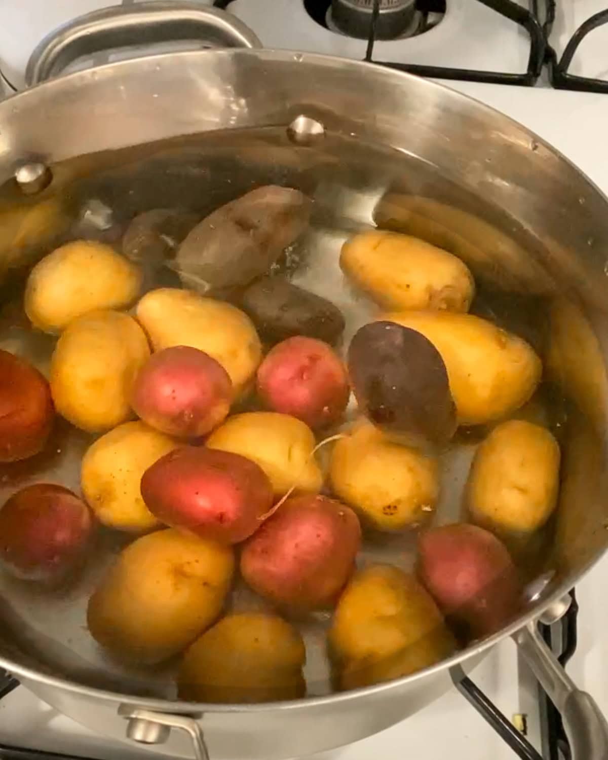 Boiling tri color potatoes in a pot with water.