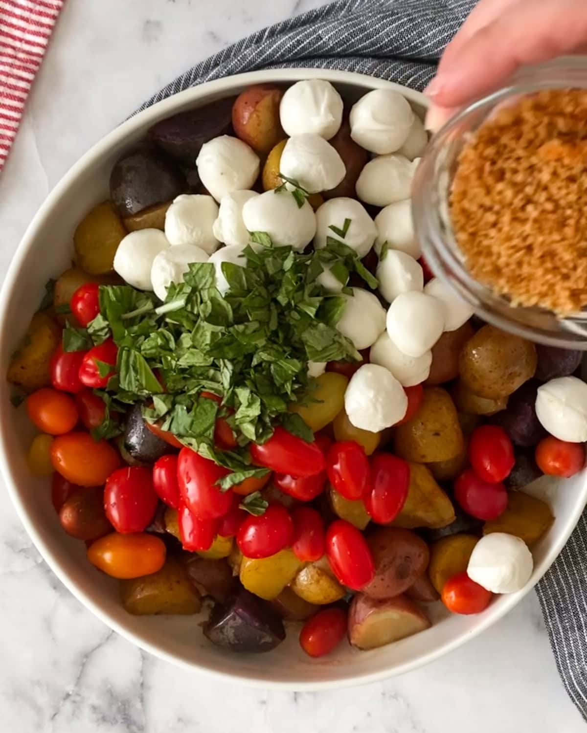 Italian potato salad in bowl with ingredients being mixed together