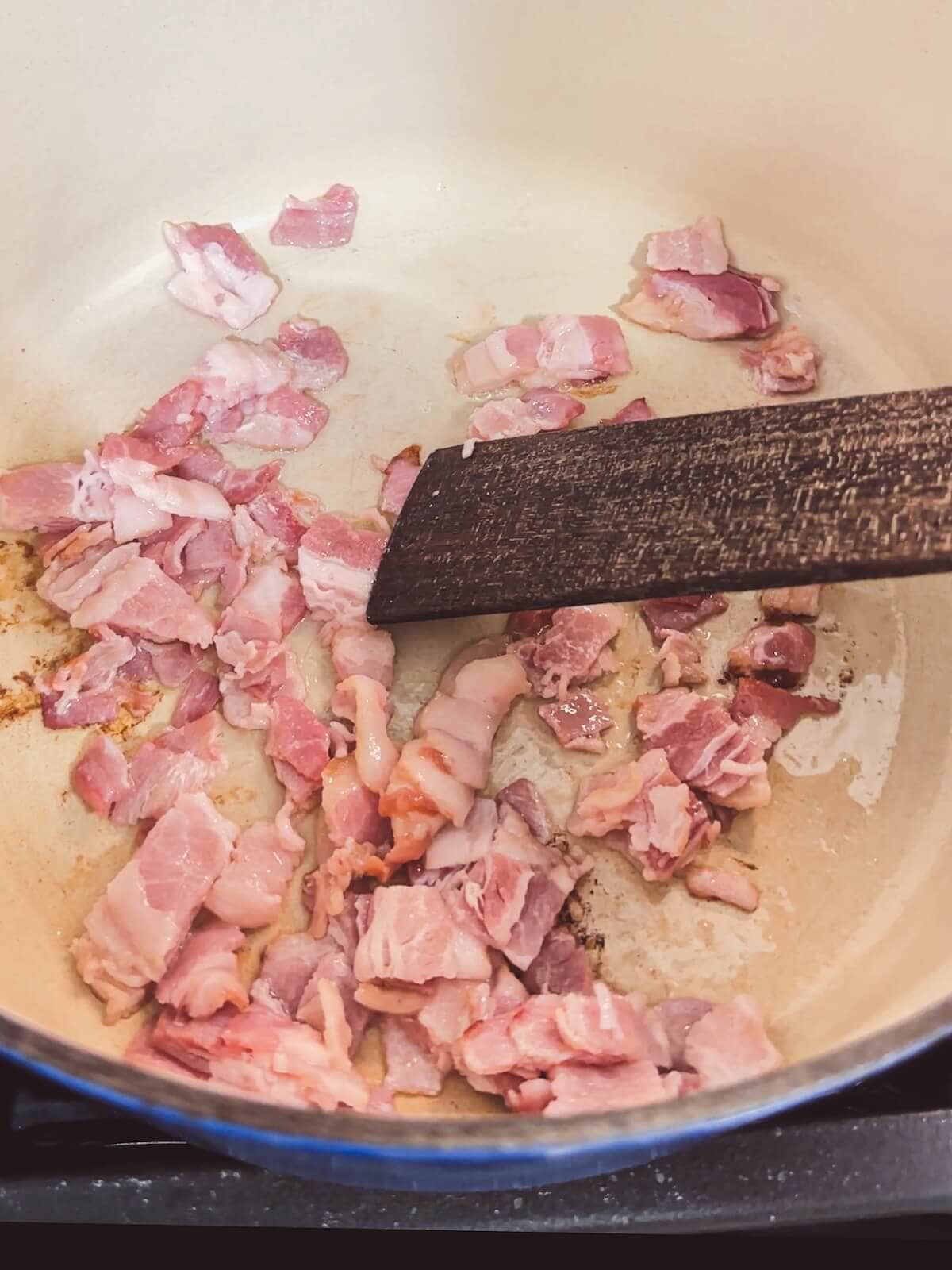 Cooking bacon pieces in a large pot. 