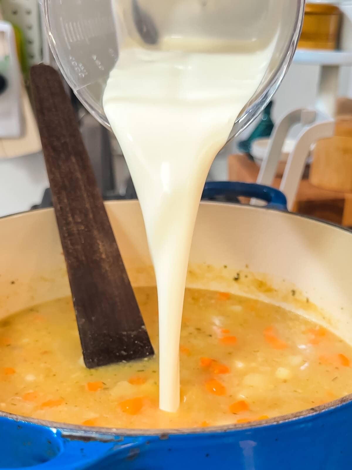 Cream being poured into a pot of potato soup.