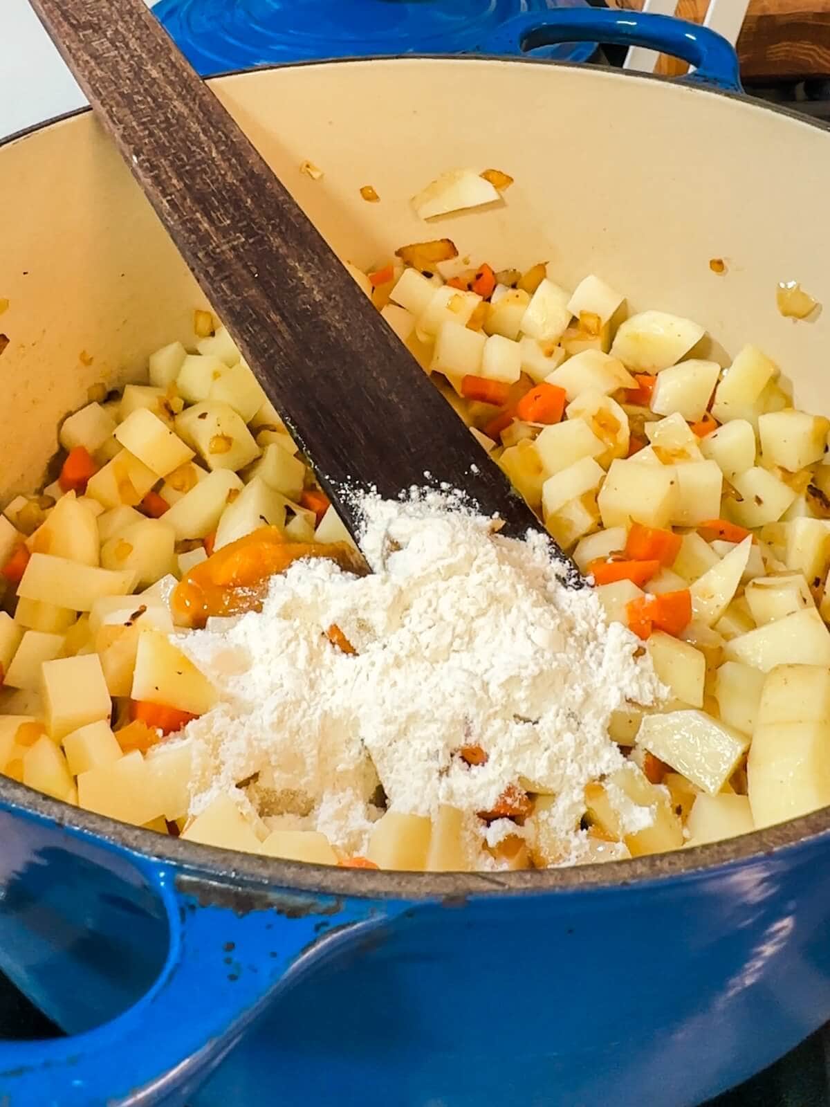 Stirring flour into the vegetables for potato soup.