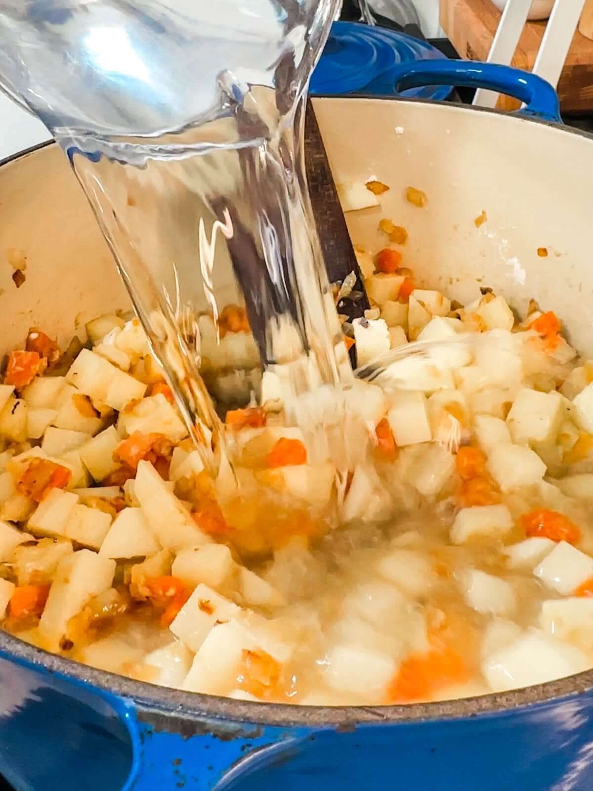 Water being added to a soup pot to make potato soup.