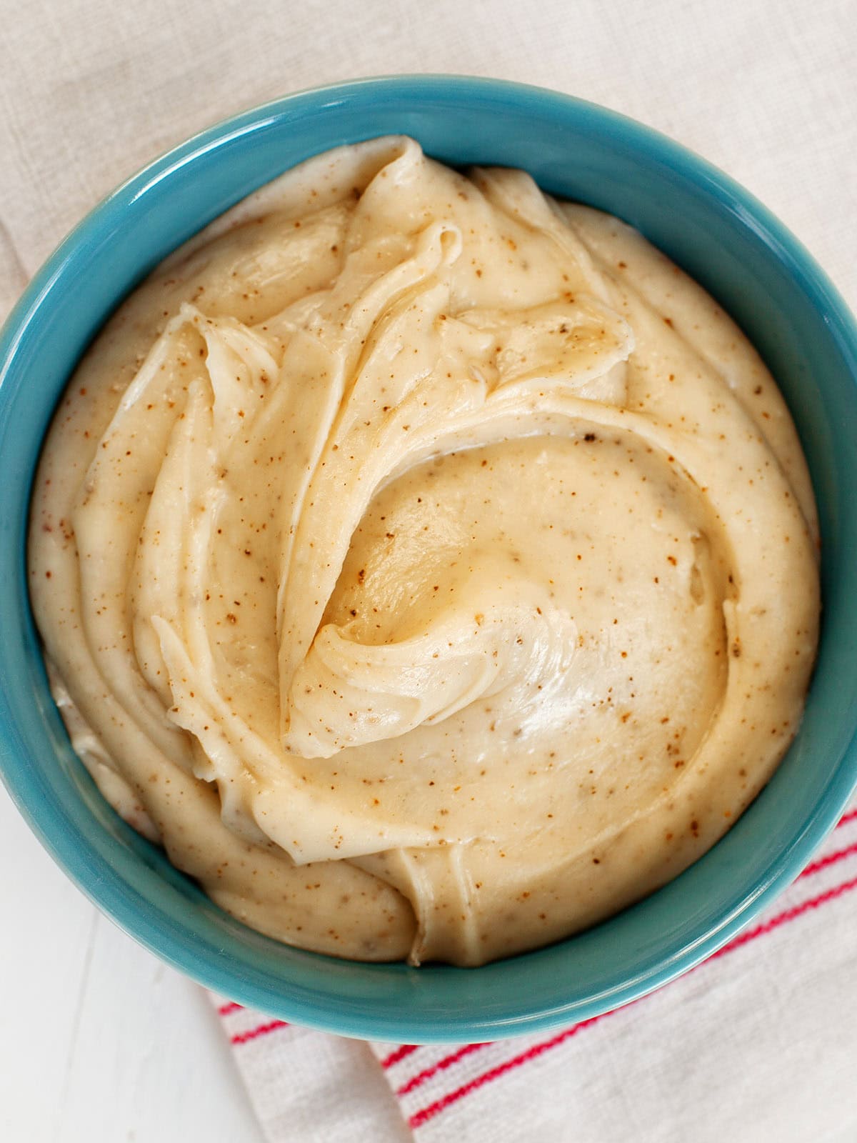 Top view of a teal bowl filled with browned butter frosting.