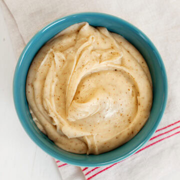 Top view of a teal bowl filled with brown butter frosting.
