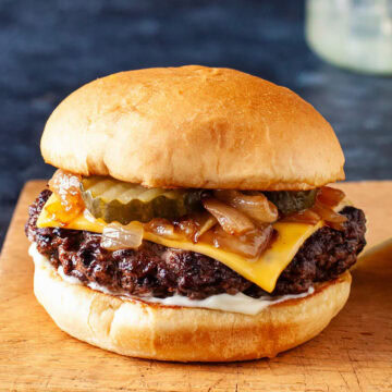 Close up of a butter burger on a wooden cutting board.