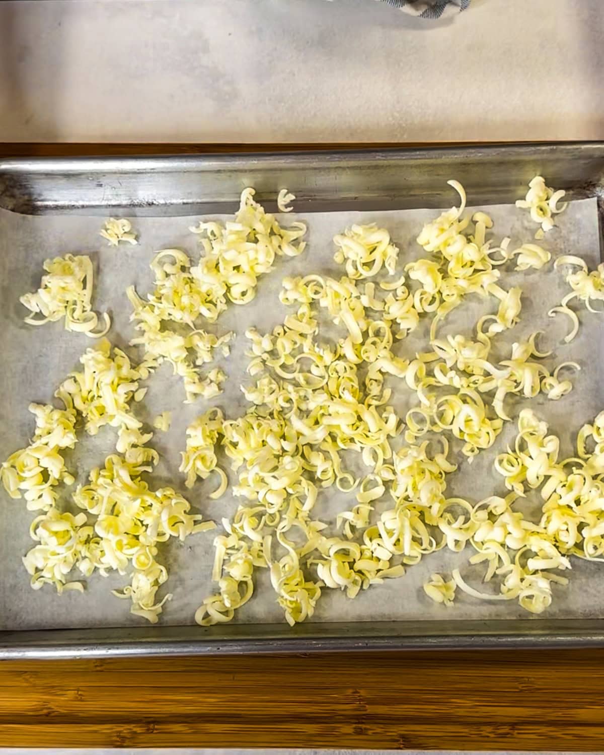 Grated butter shreds on a parchment-lined baking sheet.