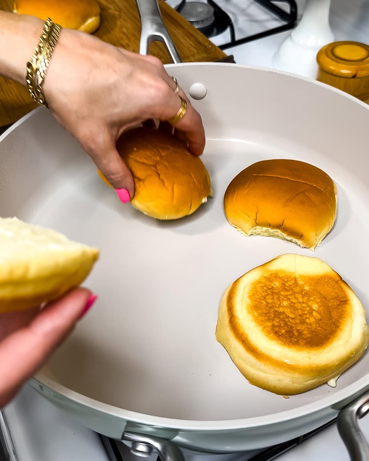 Toasting buns in a skillet on the stovetop.