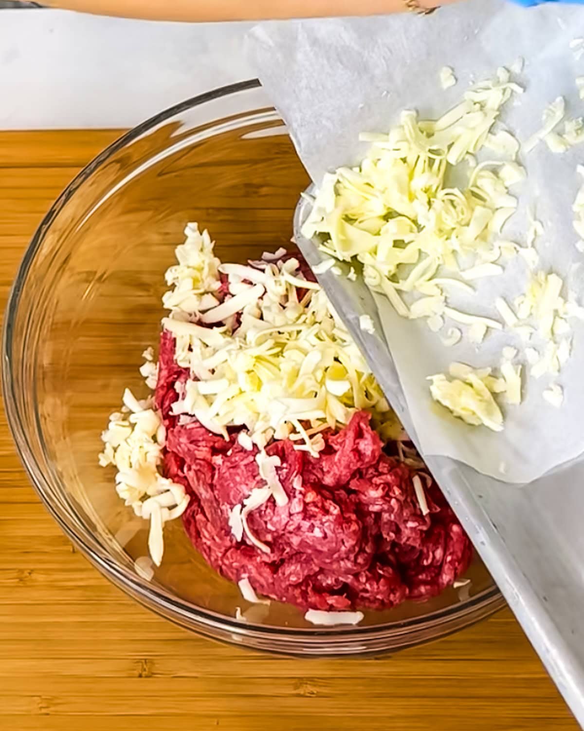 Cold butter being added to ground beef in a mixing bowl. 