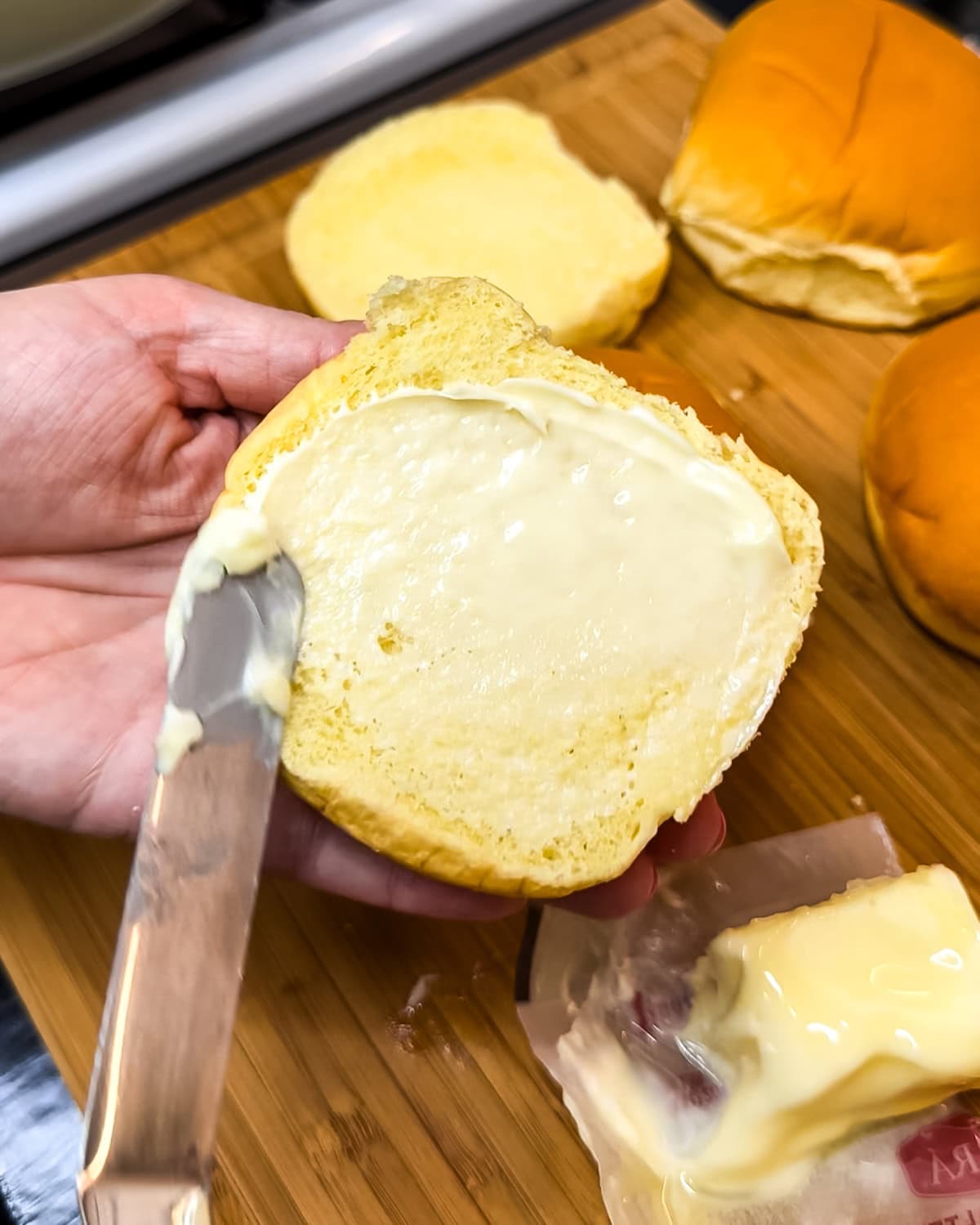 Using a butter knife to spread butter on a bun. 