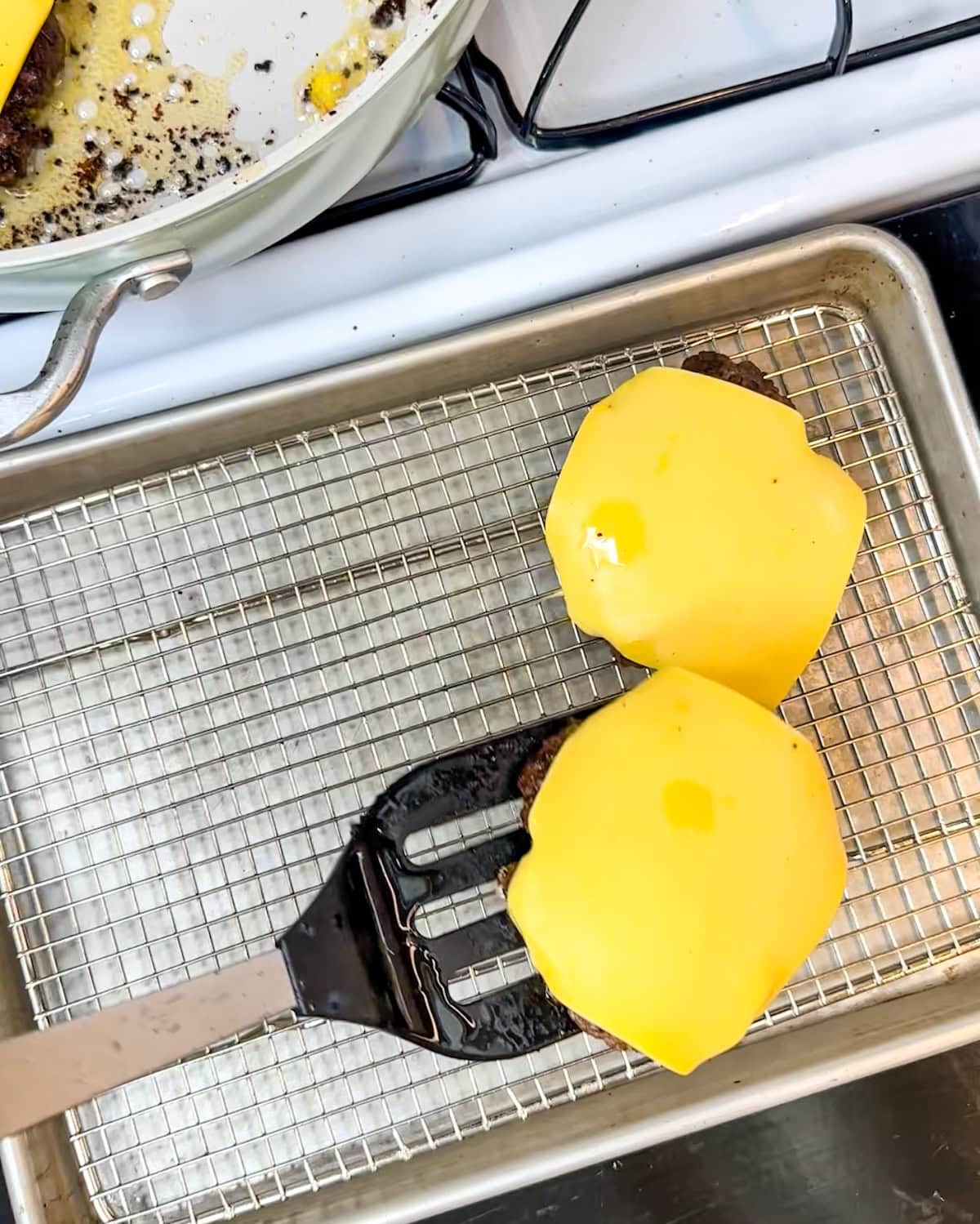 Placing a cooked butter burger on a wire rack to drip.