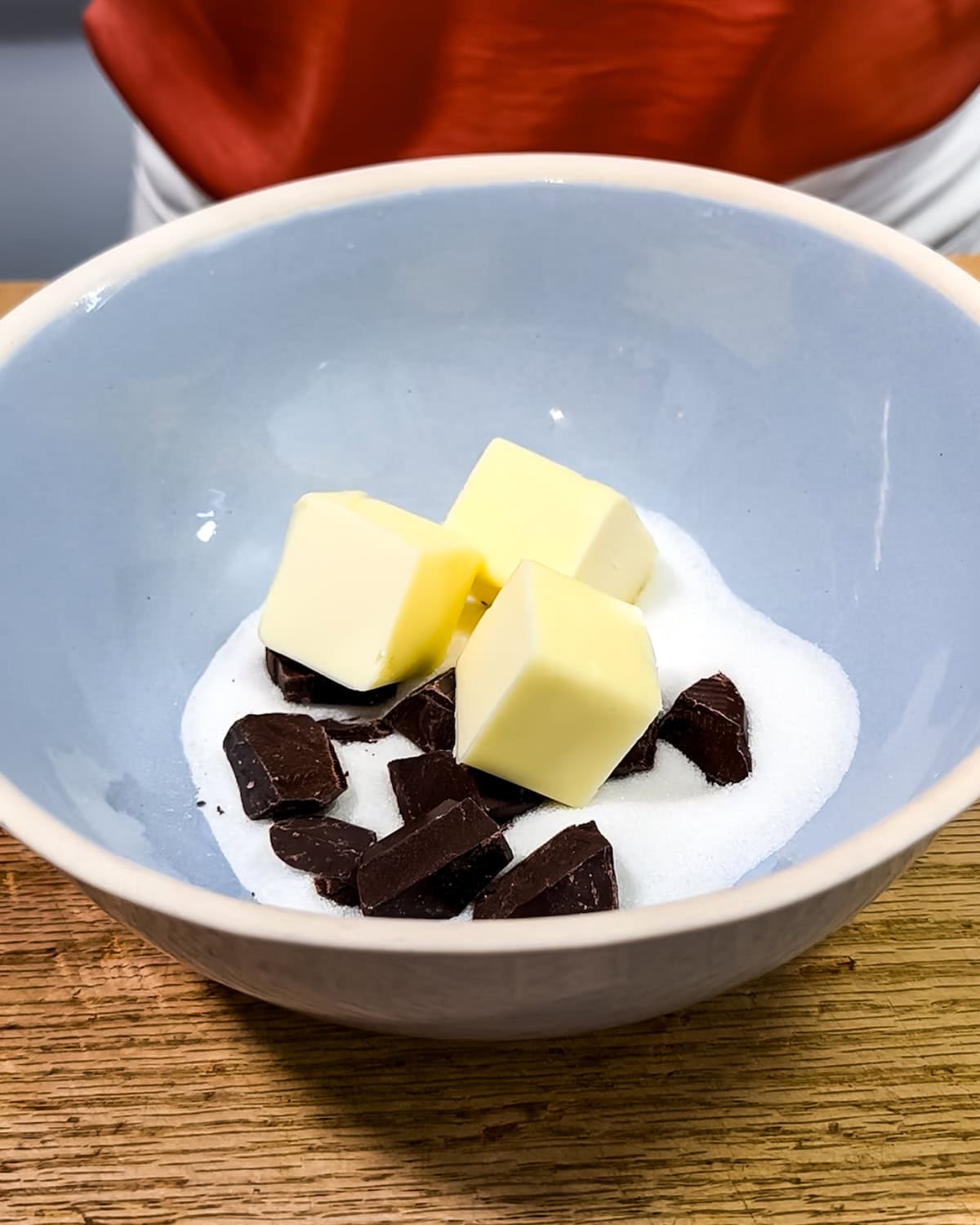 Cubed butter, sugar and chocolate in a mixing bowl.