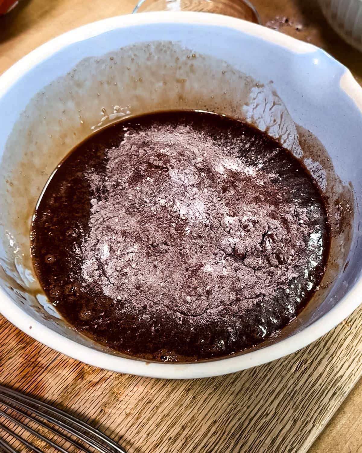 Dry mixture being added to wet chocolate cake mixture. 