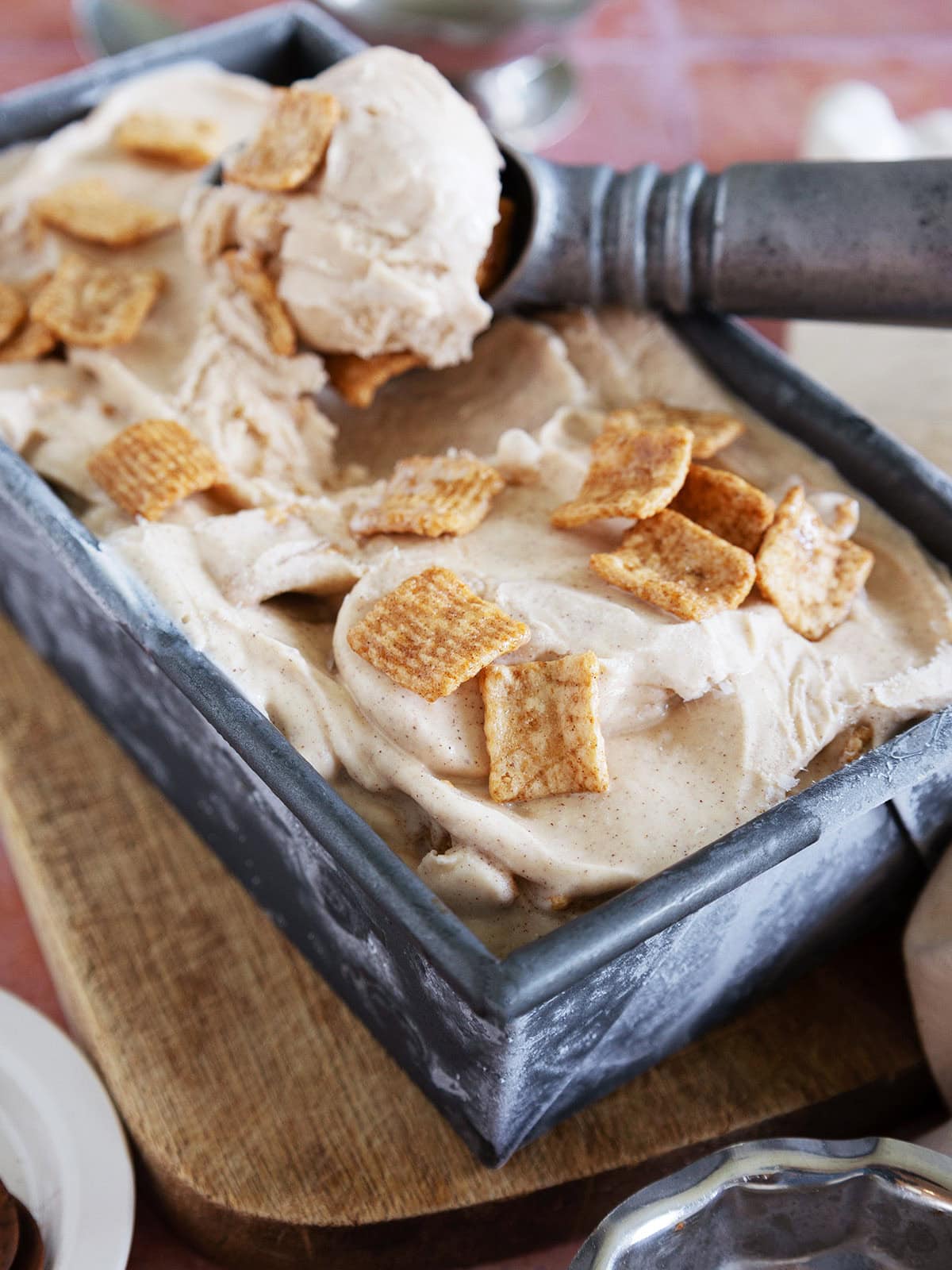 Close up of a pan of cinnamon toast crunch ice cream with a scooper scooping out ice cream. 