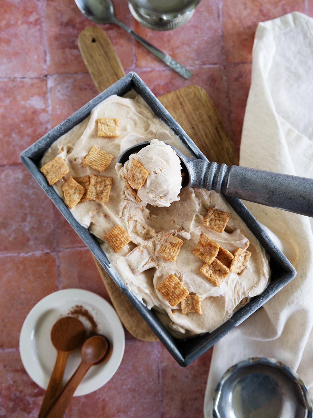 Top view of a loaf pan and ice cream scooper of cinnamon toast crunch ice cream.