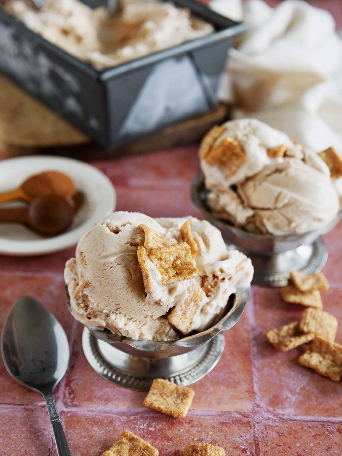 A metal dessert bowl filled with scoops of cinnamon toast crunch ice cream.