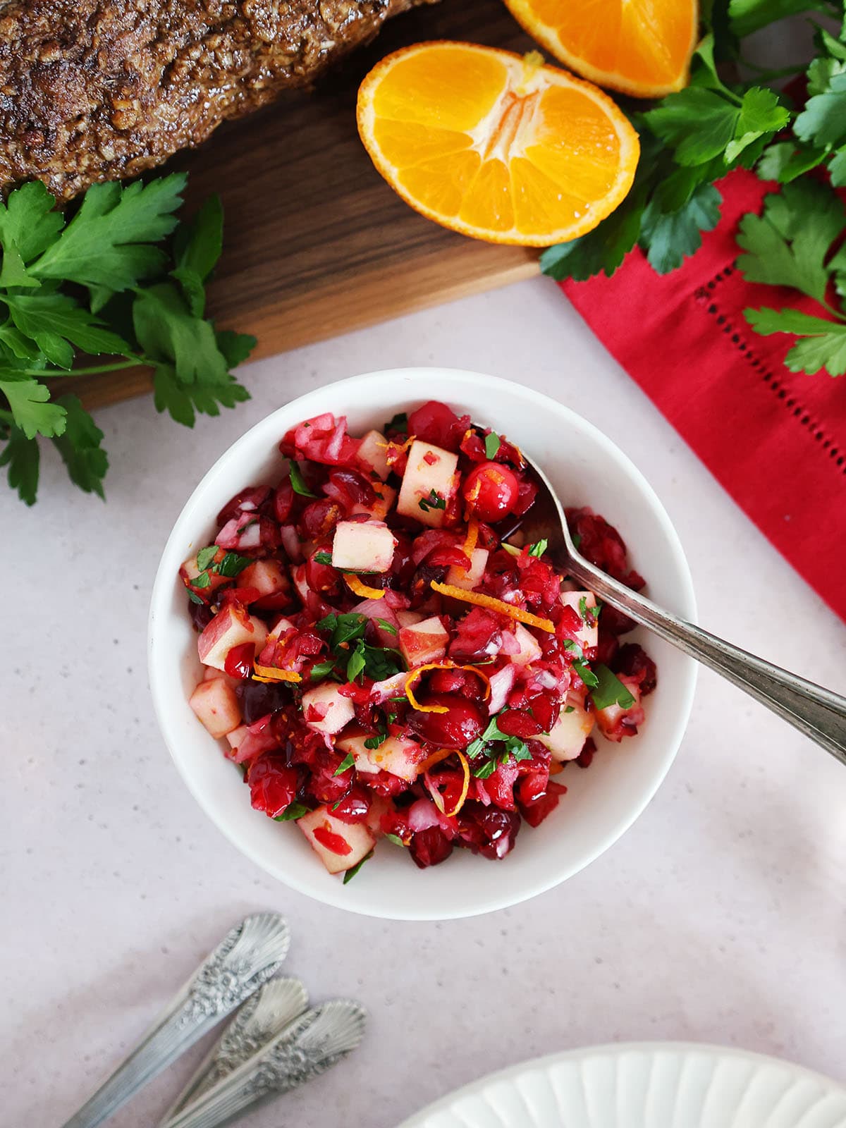Top view of a bowl of cranberry relish with other ingredients in the background. 