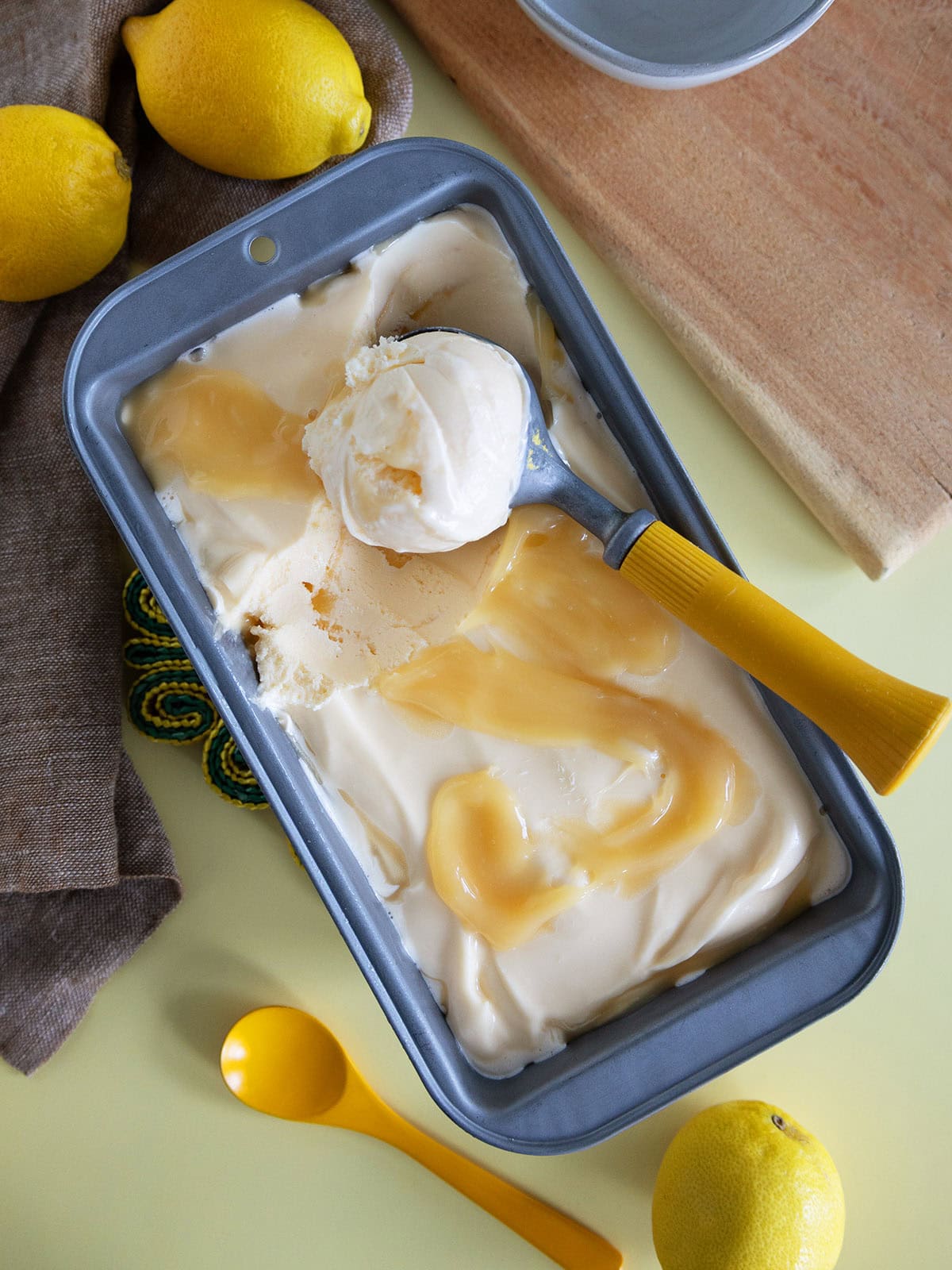 Top view of a loaf pan with a scooper holding a scoop of ice cream.