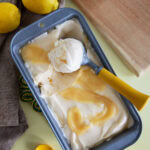 Top view of a loaf pan of lemon curd ice cream with an ice cream scoop.