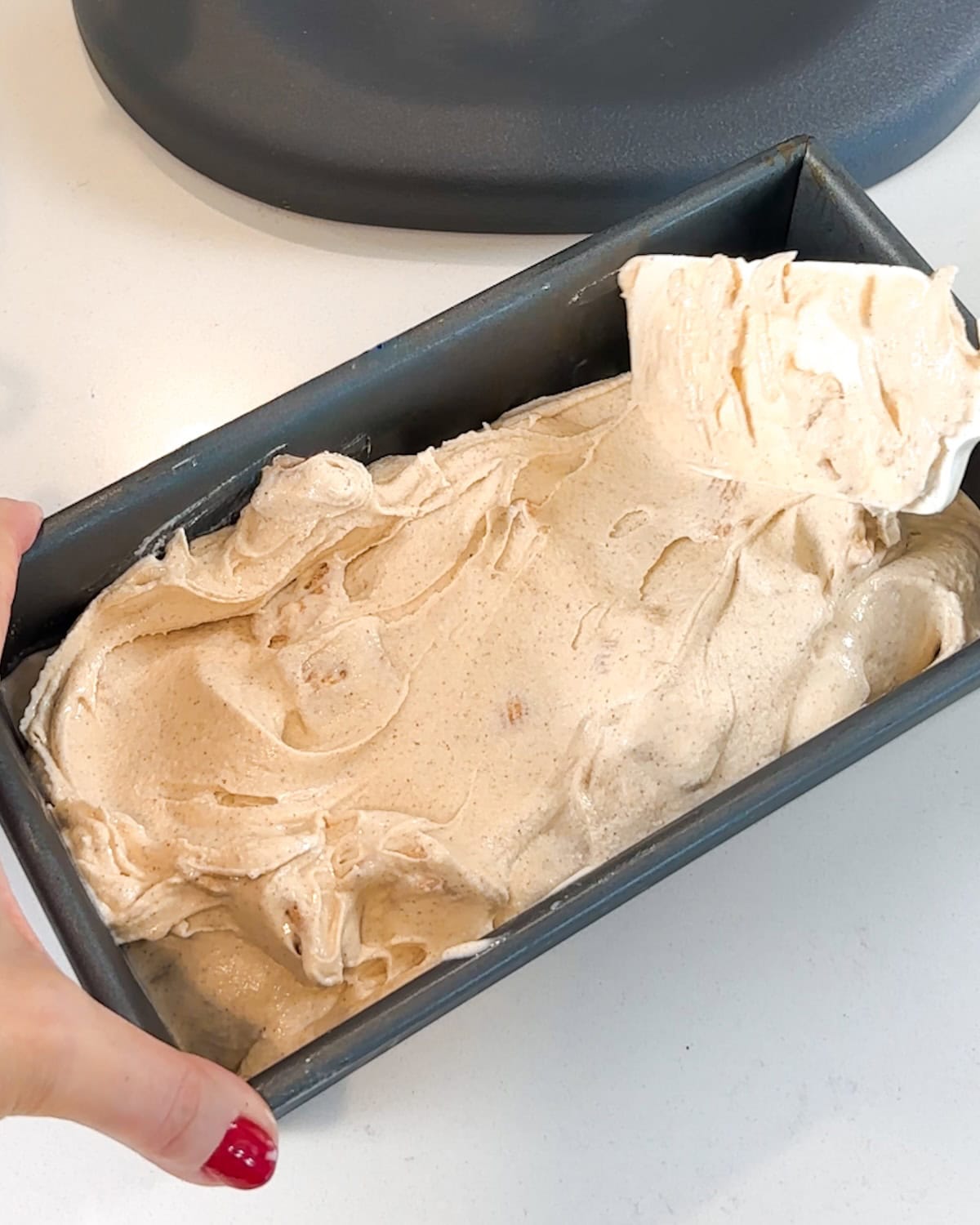 Spreading ice cream into a loaf pan with a spatula.