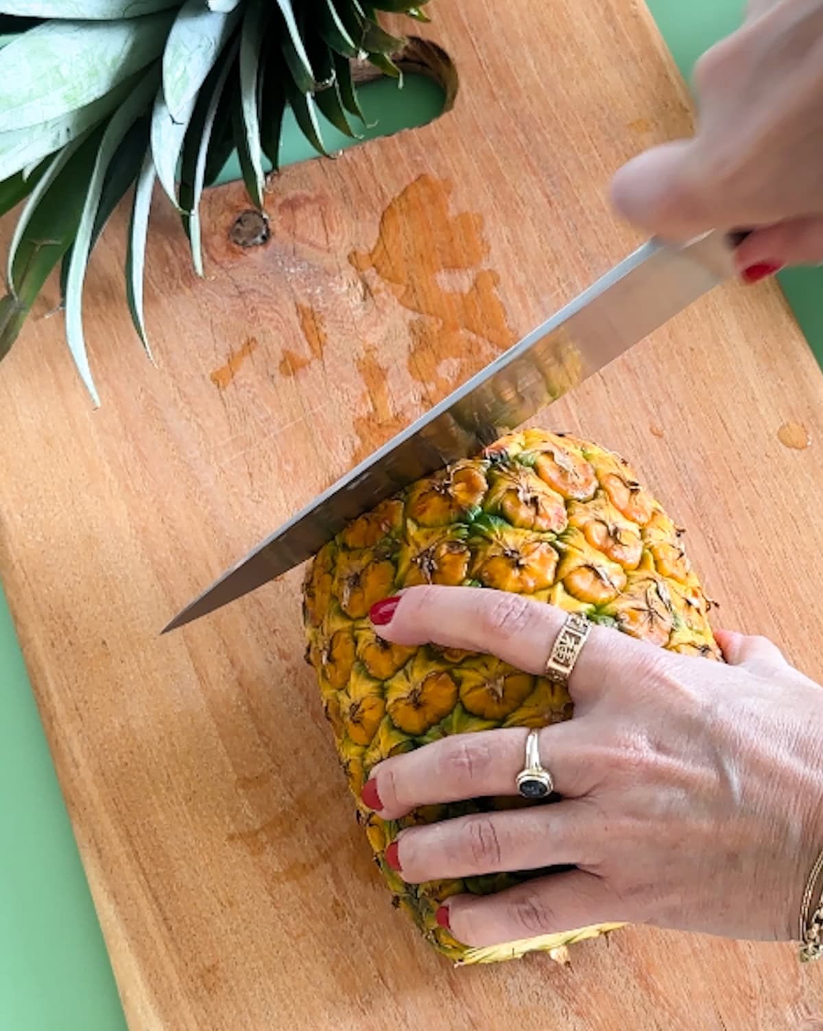 cutting the top and bottom off pineapple to prepare it for grilling.