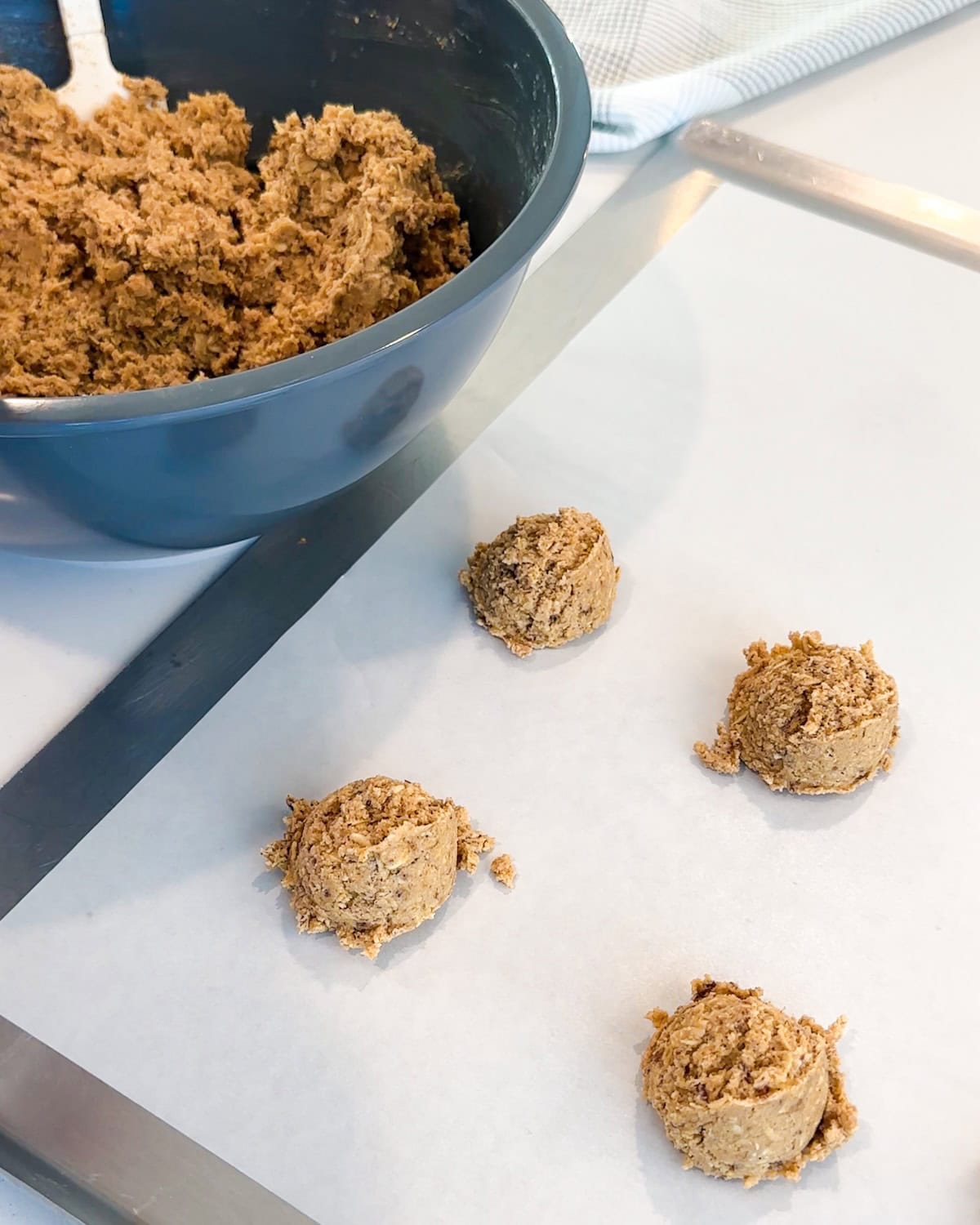 oatmeal cookie dough scooped onto a lined baking sheet.